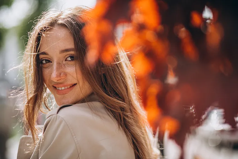 Eine Frau mit sanften Lächeln in herbstlicher Outdoor-Umgebung